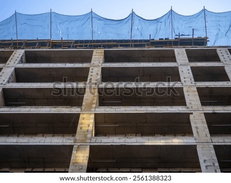Construction nets on an unfinished building. Construction industry. Cement and concrete. Safety