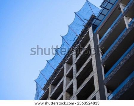 Construction nets on an unfinished building. Construction industry. Cement and concrete. Safety