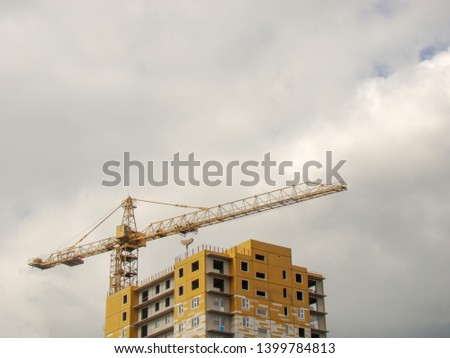 Construction of a new apartment building. Works crane. Sky background.                              