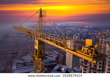 Construction of new multi-storey buildings. Construction crane at dawn on a construction site. View from the drone. Morning fog on the horizon.
