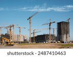 Construction of a new residential complex. Many high-rise cranes and industrial construction equipment against the backdrop of a construction buildings.