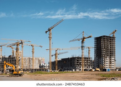 Construction of a new residential complex. Many high-rise cranes and industrial construction equipment against the backdrop of a construction buildings.