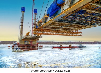 Construction new road bridge continues across the Sheksna river  Cable  stayed bridge in Cherepovets at sunset  Fragment the unfinished construction the city highway Cargo barge ice  
