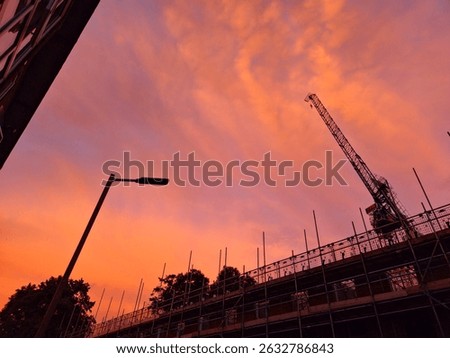 Construction with a an orange sandy sunset sky with a lampost in view.