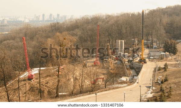 Construction, panorama of the city, construction\
work in the park, cars, crane, sand, trees, spring, city,\
construction site, production\
process
