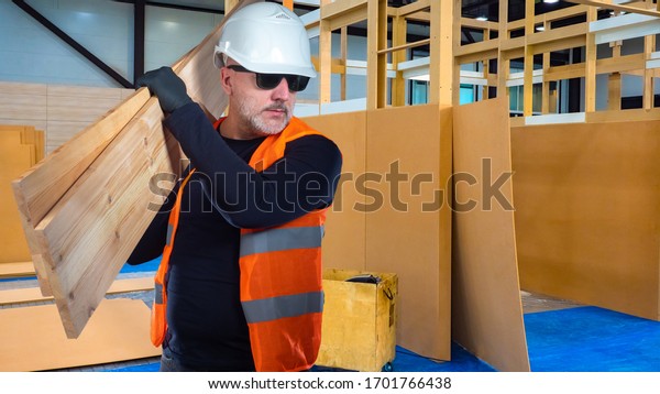 Construction of\
partitions in the building. The man with the boards. Zoning of\
space. The large room is divided into rooms using boards and\
plywood. Lumber in\
construction.