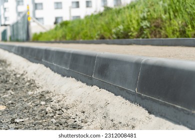 Construction of a pedestrian path. Paving of pedestrian paths on city streets. Road curbs and sidewalks. New curbs close up. Curbs detail. Soft focus.
