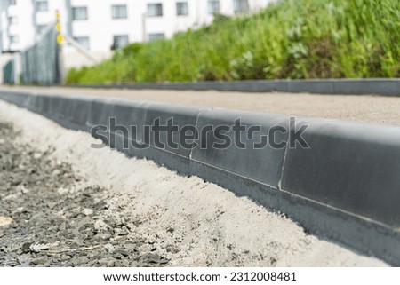 Construction of a pedestrian path. Paving of pedestrian paths on city streets. Road curbs and sidewalks. New curbs close up. Curbs detail. Soft focus.