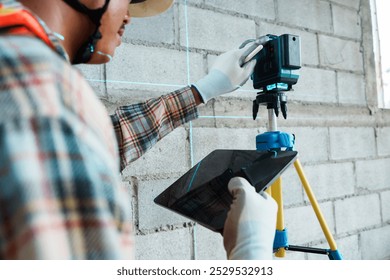A construction professional using a laser level for precise measurements on-site, ensuring accuracy and efficiency in building projects.