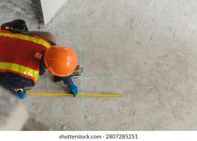 Construction professional using a laser leveling tool to accurately measure the floor layout at a busy job site