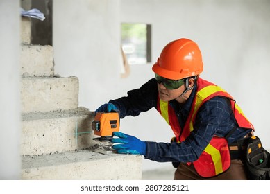 Construction professional utilizing a laser level to achieve accuracy on a staircase at a construction site