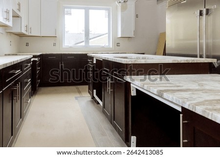 Construction is in progress in modern kitchen with dark cabinets chic marble countertops.