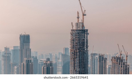 Construction progress of new modern skyscraper in Dubai city aerial timelapse, United Arab Emirates. Cranes and building equipment in downtown