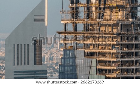 Construction progress of new modern skyscraper in Dubai city aerial timelapse, United Arab Emirates. Cranes and building equipment in financial district near downtown