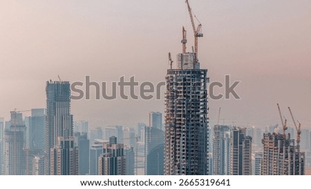 Construction progress of new modern skyscraper in Dubai city aerial timelapse, United Arab Emirates. Cranes and building equipment in downtown