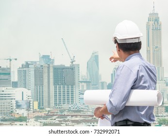 The construction project chief engineer is observing the tower crane operation at the construction site. Double exposure image