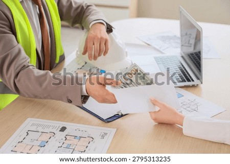 Construction project manager receiving cash payment in envelope, business transaction and financial exchange on desk with blueprints