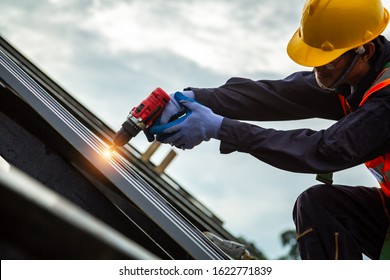 [Construction roof] Roofer worker in protective uniform wear and gloves, Construction worker install new roof,Roofing tools,Electric drill used on new roofs with Metal Sheet.