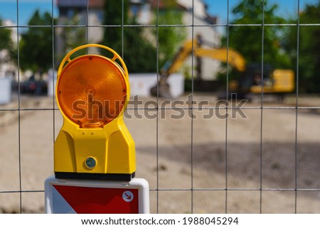 Construction safety. Street barricade with warning signal lamp on a fence. Blur site background