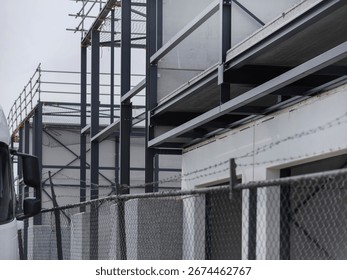 Construction scaffolding viewed through chain-link fence showing safety and security measures