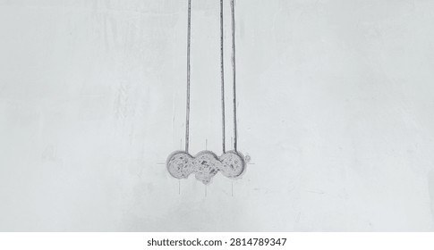 Construction scene: three vertical channels drilled into a concrete wall for wiring, with back boxes prepared for outlets.