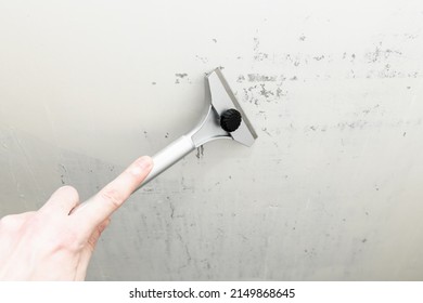 Construction scraper on gray wall background. Construction finishing works. Wall repair inside the room - Shutterstock ID 2149868645
