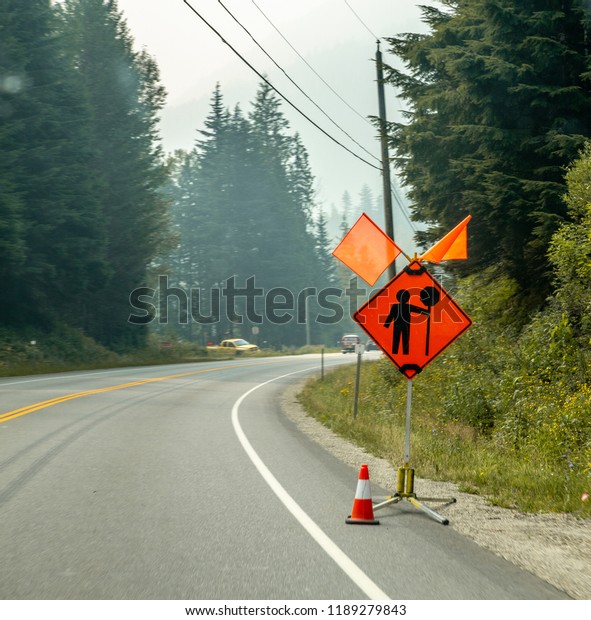 Construction sign by the road with mountain\
background in\
Canada
