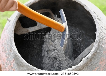 Construction site. Adding lime, sand and stones to rotating cement mixer. Builder working with shovel during concrete solution mortar preparation. Bricklayer job machine equipment. Cement slurry