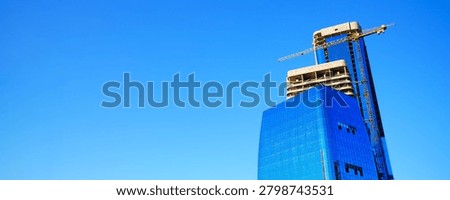Construction site banner for web site. Construction of tower skyscrapers banner on blue sky background. Tower crane on formworks buildings. Real estate market in Europe. Tower crane on construction of multifunctional complex with glass tower skyscrapers. Real estate crisis. Building construction market background.