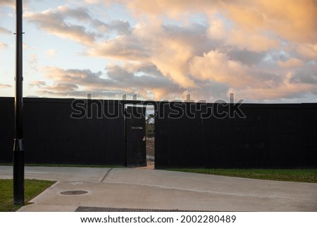 Construction site with black panel hoarding with open door access.
