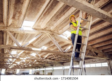 Construction site builder climbing on ladder and preparing to fix rooftop. - Shutterstock ID 1714081504