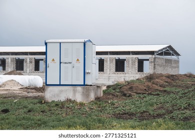Construction site with building framework, electrical transformer, and cloudy sky, emphasizing infrastructure development and rural construction projects