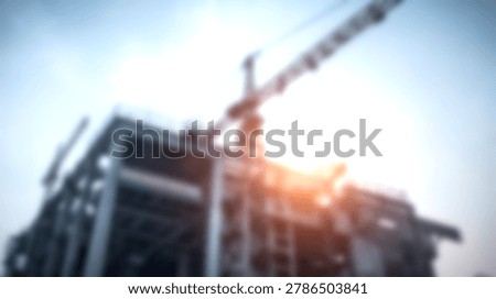 Construction site with crane and building structure against bright sky with lens flare effect.