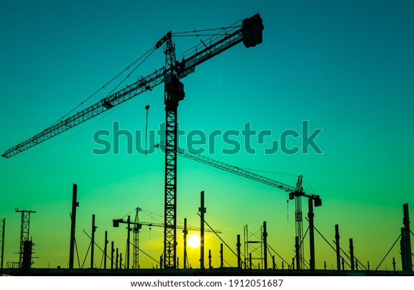 Construction site with cranes on orange\
sunset, sunrise sky background. Steel frame architect  structure,\
structural steel beam build large buildings at construction site .\
construction\
machinery.