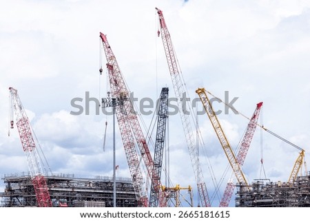 Construction site with construction crawler cranes and multi storey unfinished buildings, Many high rise cranes and industrial construction equipment, Contruction site bl;ue sky background.