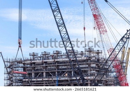 Construction site with construction crawler cranes and multi storey unfinished buildings, Many high rise cranes and industrial construction equipment, Contruction site bl;ue sky background.
