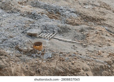 Construction site in disarray, showcasing uneven ground covered with dirt and rocks, featuring scattered materials like rusted bucket, wooden pallet, weathered plank, emphasizing work-in-progress
