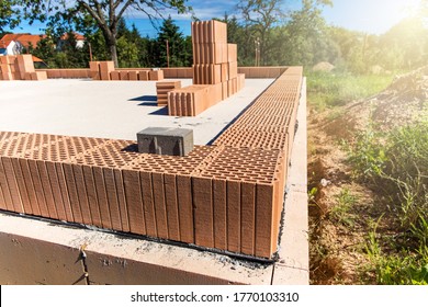 Construction site of a family house. Concrete base plate. Wall construction. Red bricks on a construction site. House construction.