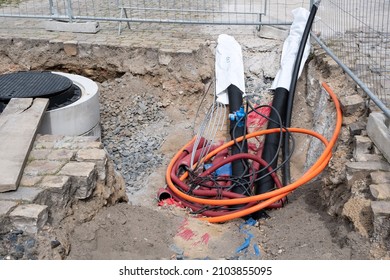 Construction site with A lot of Gigabit communication Cables Network. A large number of electric and high-speed Internet Network cables in red corrugated pipe are buried underground on the street 