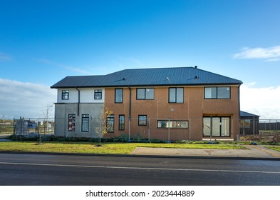 Construction Site Of A Large Two-story Residential House With Steel Roof Surrounded By Temporary Fencing Panels. Melbourne, VIC Australia.