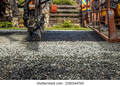 Construction site is laying new asphalt road pavement. Pours liquid asphalt, molten bitumen from a bucket of resin. - Shutterstock ID 2183164765