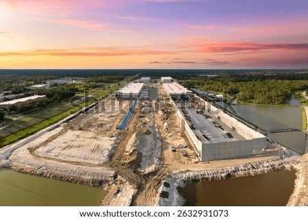 Construction site of logistic center with assembling of concrete and metal frame walls. Aerial view of large development area of commercial structure