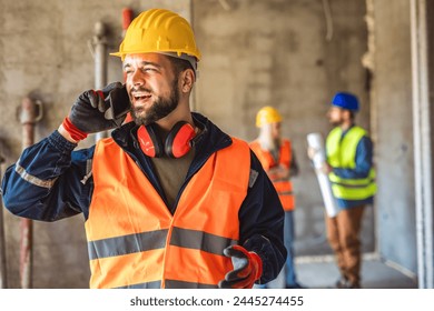 Construction site manager standing  wearing safety vest and helmet, talking to the phone at construction site.  - Powered by Shutterstock