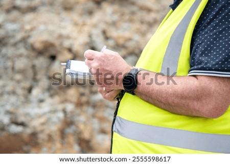Construction site manager taking notes while observing site progress onconstruction site