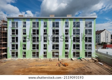 Construction site with modern apartment block, artistically designed with pattern of polygonal shapes symbolizing abstracted floral elements and sky shapes celestial forms, streetart, copy space