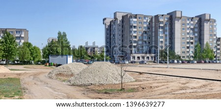 Construction site of a new car parking in a standard residential area with mass production buildings. Sunny spring day panoramic urban landscape