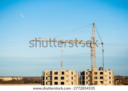 Construction site, construction of a panel house in process, aerial view, a tower crane moving a panel slab