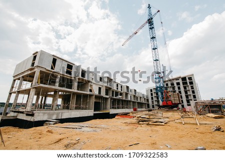  construction site of residential buildings with cranes in sunny weather with blue sky