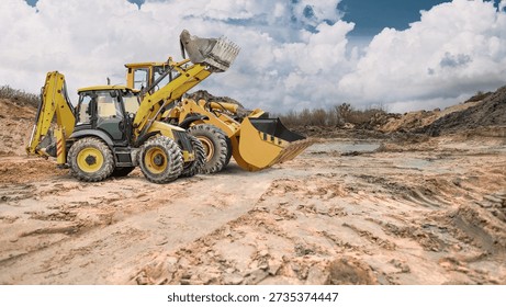 A construction site or sand pit with two powerful wheeled front loaders ready to go, under partly cloudy skies during the day.