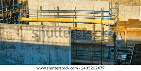 A construction site with scaffolding and a wall in the background. Scene is one of progress and hard work